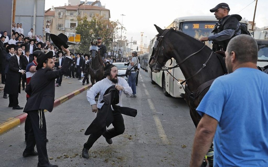 A horse-mounted police officer disperses ultra-Orthodox Jewish demonstrators during a protest against military conscription in Bnei Brak, a city near Tel Aviv, on November 20, 2017. (AFP Photo/Ahmad Gharabli)