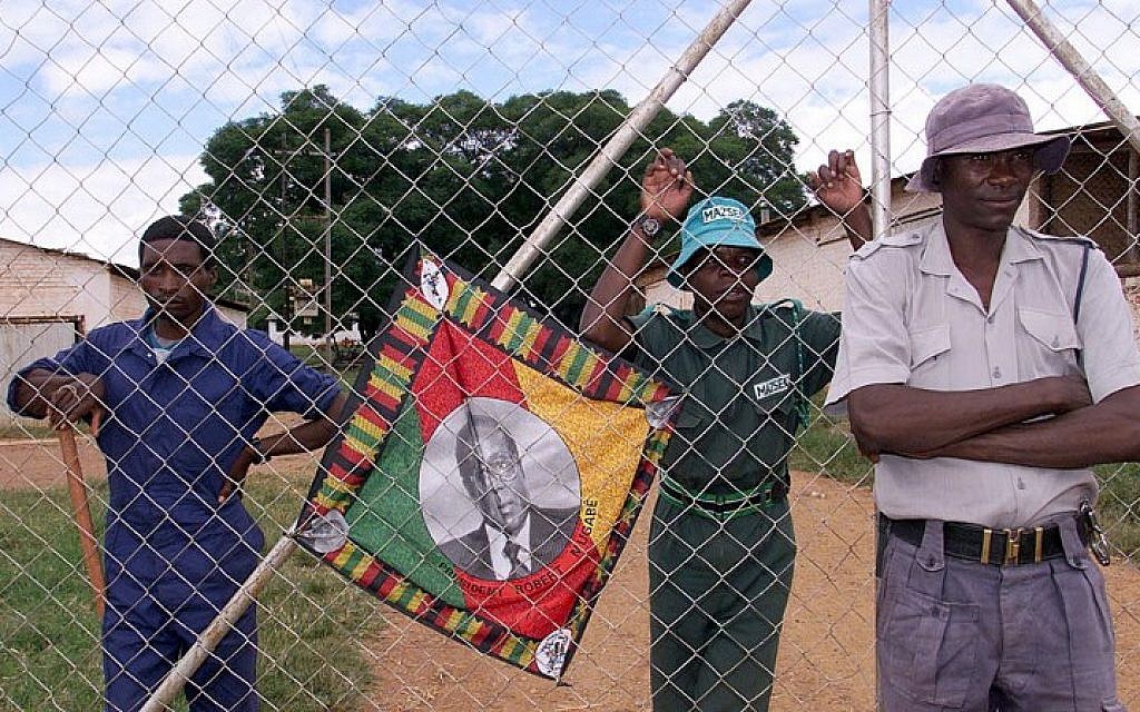 This file photo taken on April 10, 2000 shows a policeman and black squatters guarding the farm of expelled white farmer Rob Marshell, in Mazowe, some 60 kilometers north of Harare. A portrait of President Robert Mugabe who encouraged the squatters to step up the occupations of white-owned farms, is seen on the fence.
(AFP PHOTO / ALEXANDER JOE) This file photo taken on April 10, 2000 shows a policeman and black squatters guarding the farm of expelled white farmer Rob Marshell, in Mazowe, some 60 kilometers north of Harare. A portrait of President Robert Mugabe who encouraged the squatters to step up the occupations of white-owned farms, is seen on the fence.
(AFP PHOTO / ALEXANDER JOE)