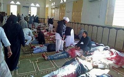 Egyptians walk past bodies following a gun and bombing attack at the Rawda mosque, roughly 40 kilometers west of the North Sinai capital of El-Arish, on November 24, 2017. (AFP PHOTO / STRINGER