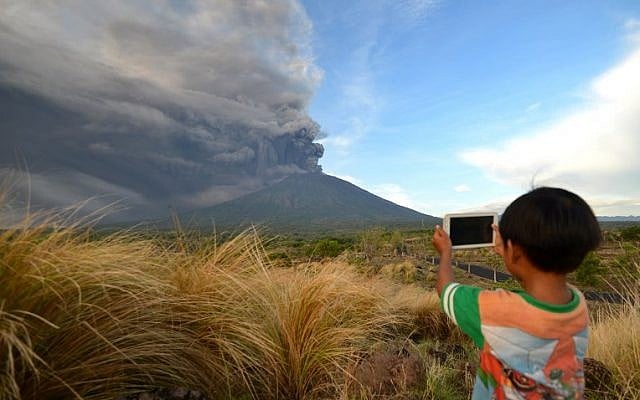 A boy takes pictures of Mount Agung as seen from Kubu sub-district in Karangasem Regency on Indonesia's resort island of Bali on November 26, 2017. (AFP PHOTO / SONNY TUMBELAKA) A boy takes pictures of Mount Agung as seen from Kubu sub-district in Karangasem Regency on Indonesia's resort island of Bali on November 26, 2017. (AFP PHOTO / SONNY TUMBELAKA)