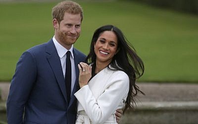 Britain's Prince Harry stands with his fiancée US actress Meghan Markle as she shows off her engagement ring whilst they pose for a photograph in the Sunken Garden at Kensington Palace in west London on November 27, 2017, following the announcement of their engagement. (AFP PHOTO / Daniel LEAL-OLIVAS)