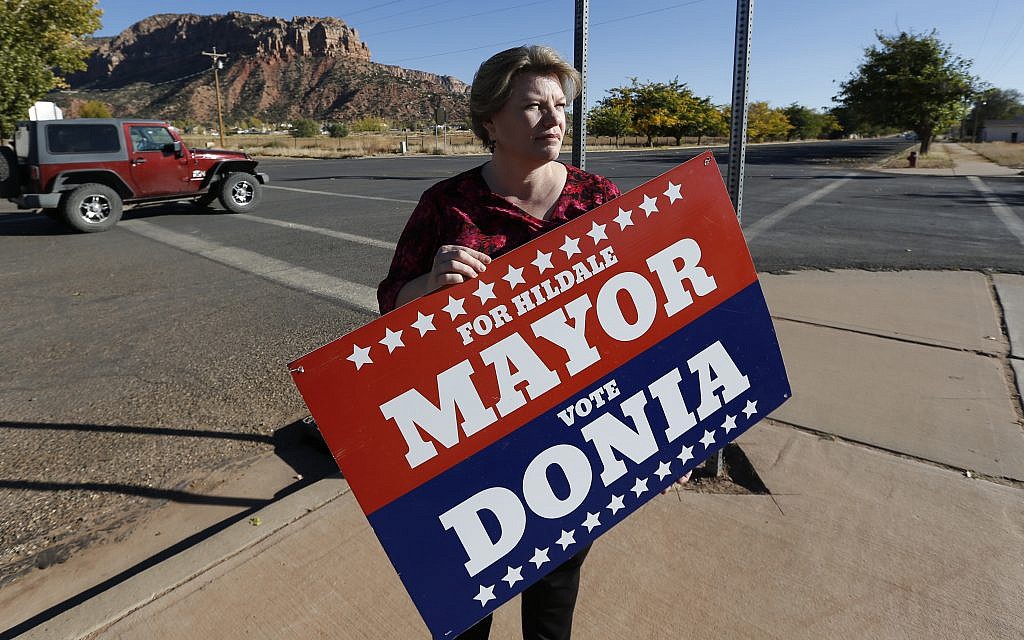 In this October 26, 2017 photo, Donia Jessop holds her mayoral campaign sign outside her store in Colorado City, Ariz. (AP Photo/Rick Bowmer) In this October 26, 2017 photo, Donia Jessop holds her mayoral campaign sign outside her store in Colorado City, Ariz. (AP Photo/Rick Bowmer)