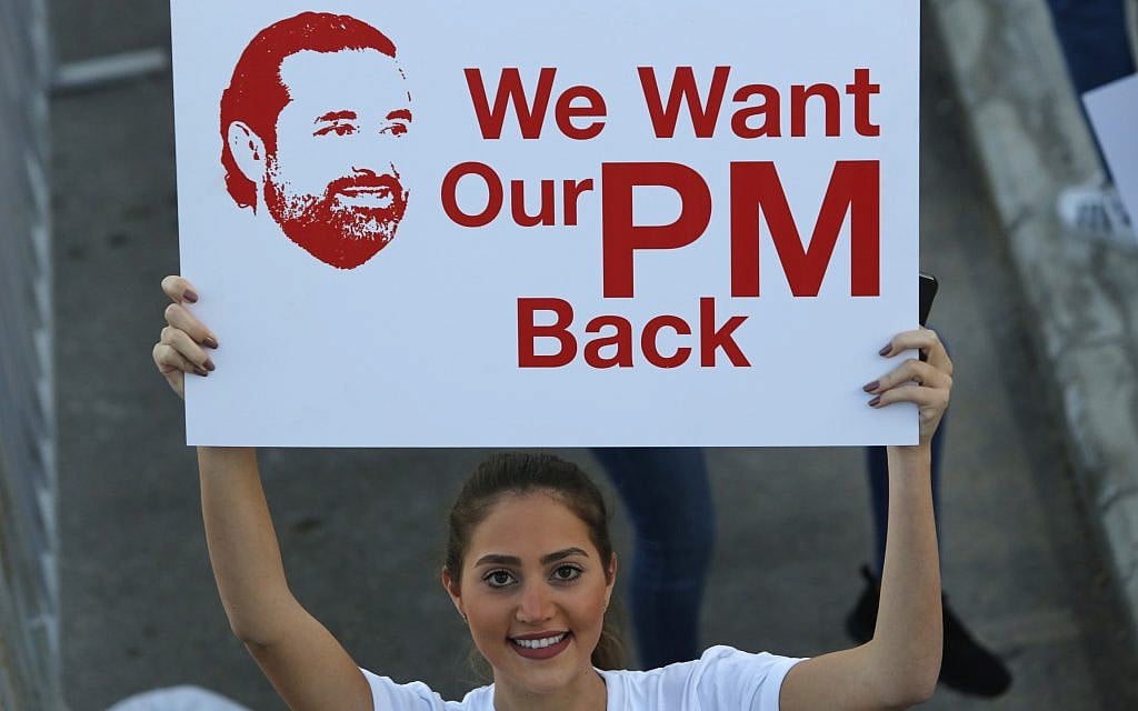 A Lebanese woman holds a placard supporting the outgoing Lebanese Prime Minister Saad Hariri to return from Saudi Arabia during the Beirut Marathon, in Beirut, Lebanon, November 12, 2017. (AP Photo/Hassan Ammar)