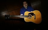 Garry Shrum, a music memorabilia specialist at Heritage Auctions, displays an acoustic guitar that belonged to Bob Dylan in Dallas, on October 13, 2017. (AP Photo/LM Otero)