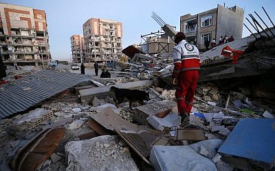 A rescue worker searches debris for survivors with his sniffing dog after an earthquake at the city of Sarpol-e-Zahab in western Iran, November 13, 2017. (Pouria Pakizeh/ISNA via AP)