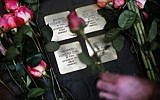Roses are laid on four "Stolpersteine" (stumbling blocks) for Karolina Cohn and her family in Frankfurt, Germany, Monday, Nov. 13, 2017. (AP Photo/Michael Probst)