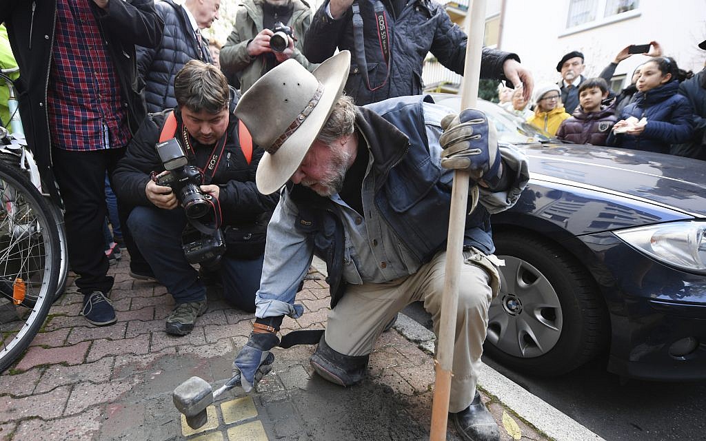 Artist Gunter Demnig lays four 'Stolpersteine,' or stumbling stones, a Holocaust commemoration, for Karolina Cohn and her family in Frankfurt, Germany, November 13, 2017. (Arne Dedert/dpa via AP)