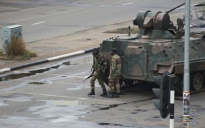 A military armored personnel carrier is seen with armed soldiers on the road leading to President Robert Mugabe's office in Harare, Zimbabwe Wednesday, Nov. 15, 2017. (AP Photo/Tsvangirayi Mukwazhi)