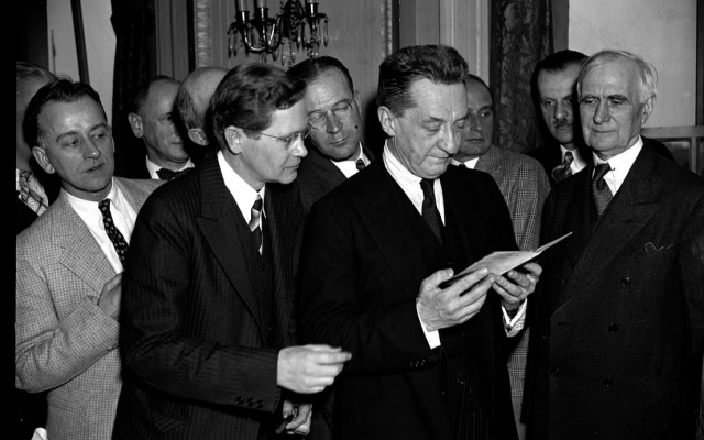 In this 1938 photo taken in Washington, DC, Alexander Kerensky examines a passport he signed for an American Red Cross member in 1917. (Public domain)