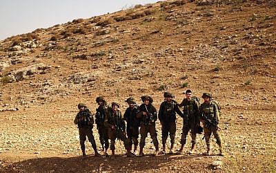 Soldiers smile after 'conquering' a hill as part of a training exercise in the Jordan Valley on November 28, 2017. (Judah Ari Gross/Times of Israel)