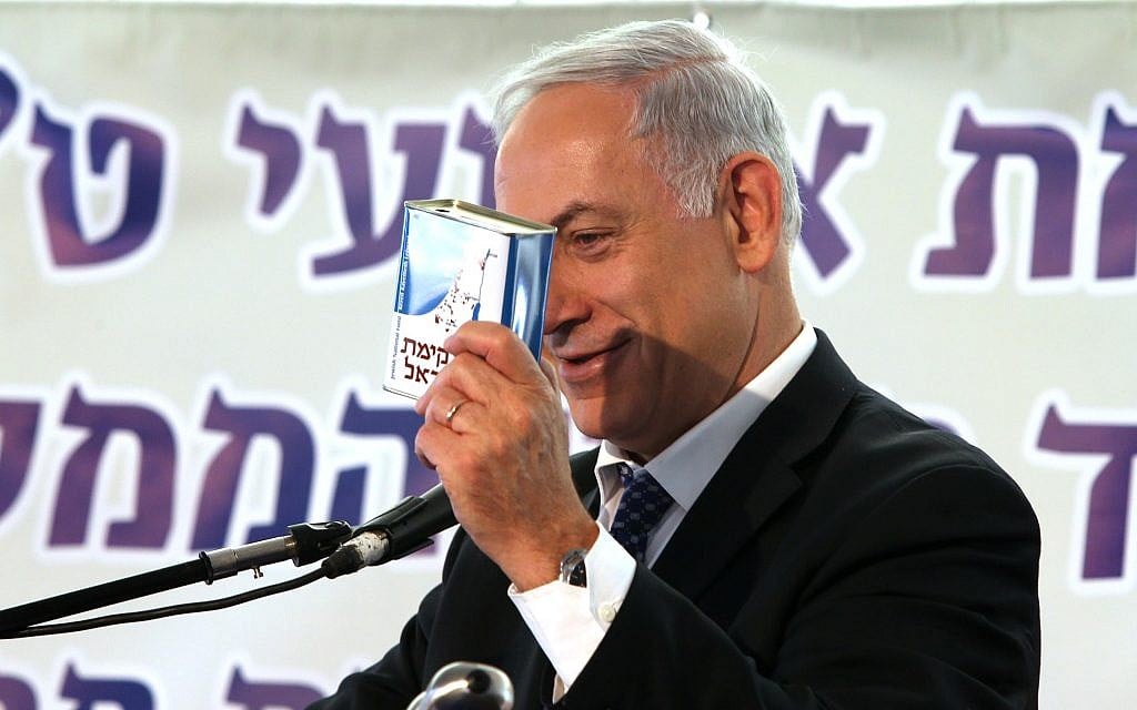 Prime Minister Benjamin Netanyahu holding KKL-JNF collection box at a tree planting ceremony in the Jerusalem forest on January 15, 2014. (Amit Shabi/Pool/Flash 90)