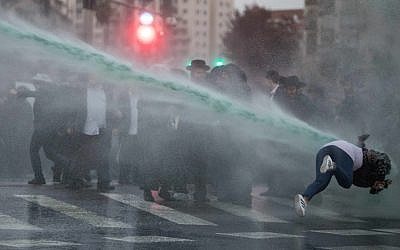 A jet of anti-riot skunk water sends a woman reeling as ultra-Orthodox Jews protest the jailing of draft dodgers, Jerusalem, November 27, 2017. (Flash90)