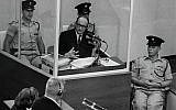 Nazi war criminal Adolf Eichmann stands in a protective glass booth flanked by Israeli police during his trial June 22, 1961, in Jerusalem. (Photo by GPO)