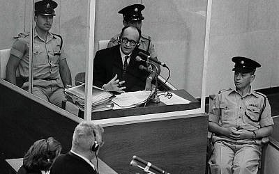 Nazi war criminal Adolf Eichmann stands in a protective glass booth flanked by Israeli police during his trial June 22, 1961, in Jerusalem. (Photo by GPO)