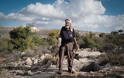 Avraham Herzlich stands next to an ancient mikveh in the fields near his home in Kfar Tapuah. (Luke Tress/Times of Israel)