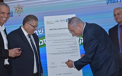 Prime Minister Benajmin Netanyahu (r) signs a deal for new housing in the northern town of Migdal Haemek on November 6, 2017. (Migdal Haemek)