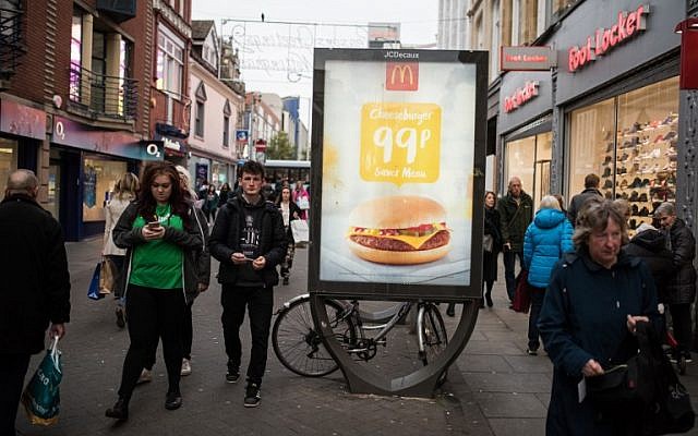 People walk by an advertisement for McDonald's in Nottingham, England, on November 17, 2017. (AFP Photo/Oli Scarff) People walk by an advertisement for McDonald's in Nottingham, England, on November 17, 2017. (AFP Photo/Oli Scarff)