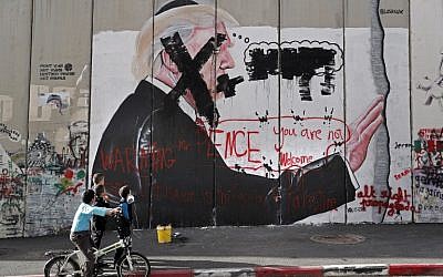 Palestinian children look at graffiti depicting US President Donald Trump and slogans against US Vice President Mike Pence painted on Israel's security barrier in the West Bank city of Bethlehem during clashes with Palestinian protesters near an Israeli checkpoint on December 7, 2017. (AFP/Thomas Coex)