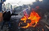 A Palestinian protester sets alight an America flag during clashes with Israeli troops at a protest against US President Donald Trump's decision to recognize Jerusalem as the capital of Israel, near the West Bank city of Ramallah on December 7, 2017.  (AFP PHOTO / ABBAS MOMANI/File)