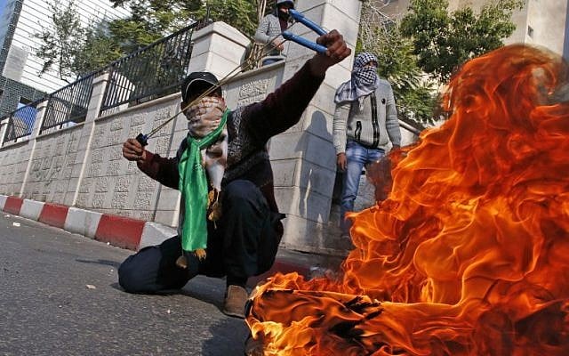 A Palestinian rioter uses a sling shot against Israeli security forces during clashes after in the West Bank city of Hebron on December 8, 2017. (Hazem Bader/AFP)