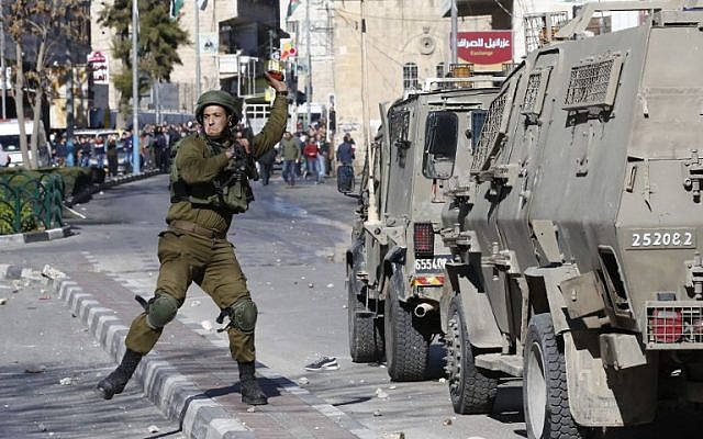 Illustrative. An Israeli soldier throws a stun grenade toward Palestinian rioters during clashes in the West Bank city of Hebron on December 8, 2017. (Hazem Bader/AFP)