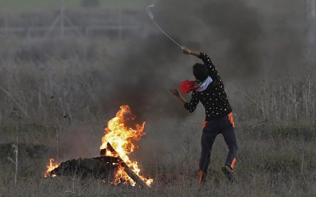 A Palestinian protester hurls a rock at Israeli forces during clashes near the Israel-Gaza border east of Gaza City on December 9, 2017, following US President Donald Trump's recognition of Jerusalem as Israel's capital. (AFP/Mahmud Hams)
