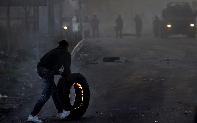A Palestinian protestor pushes a burning tire towards Israeli security forces during clashes in the West Bank city of Nablus, on December 9, 2017, following a demonstration against US President Donald Trump's decision to recognize Jerusalem as the capital of Israel. (AFP PHOTO/ AAFAR ASHTIYEH) A Palestinian protestor pushes a burning tire towards Israeli security forces during clashes in the West Bank city of Nablus, on December 9, 2017, following a demonstration against US President Donald Trump's decision to recognize Jerusalem as the capital of Israel. (AFP PHOTO/ AAFAR ASHTIYEH)