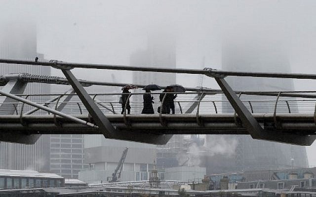 Pedestrians walk over the Millennium Bridge on a snowy day in central London on December 10, 2017. (AFP Photo/Daniel Sorabji)