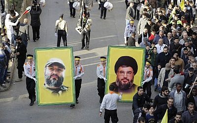 File - Supporters of Lebanon's Hezbollah terror group hold portraits of its leader Hassan Nasrallah (R) and its former military chief Imad Mughniyeh during a protest in Beirut on December 11, 2017. (AFP Photo/Joseph Eid)
