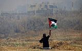 This  photo taken on May 19, 2017, shows handicapped Palestinian demonstrator Ibrahim Abu Thurayeh waving a Palestinian flag during clashes with Israeli soldiers following a protest against the blockade on Gaza, near the border fence east of Gaza City. (MOHAMMED ABED / AFP)