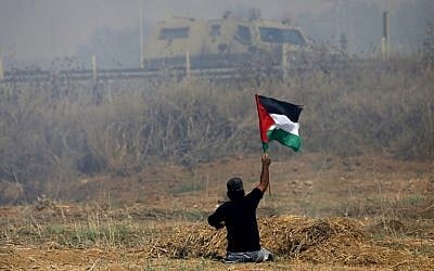 This  photo taken on May 19, 2017, shows handicapped Palestinian demonstrator Ibrahim Abu Thurayeh waving a Palestinian flag during clashes with Israeli soldiers following a protest against the blockade on Gaza, near the border fence east of Gaza City. (MOHAMMED ABED / AFP)