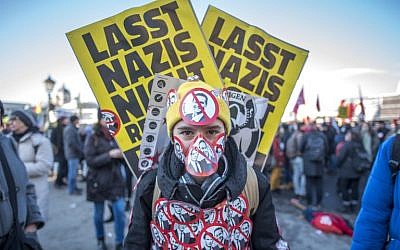 A protester stands with stickers depicting crossed out incoming vice-chancellor  of the far-right Freedom Party (FPOe) Christian Strache and incoming Austrian Chancellor of the conservative People's Party (OeVP) Sebastian Kurz during a protest near the presidential palace during the inauguration of the new Austrian government in Vienna, Austria, on December 18, 2017. (AFP PHOTO / JOE KLAMAR)