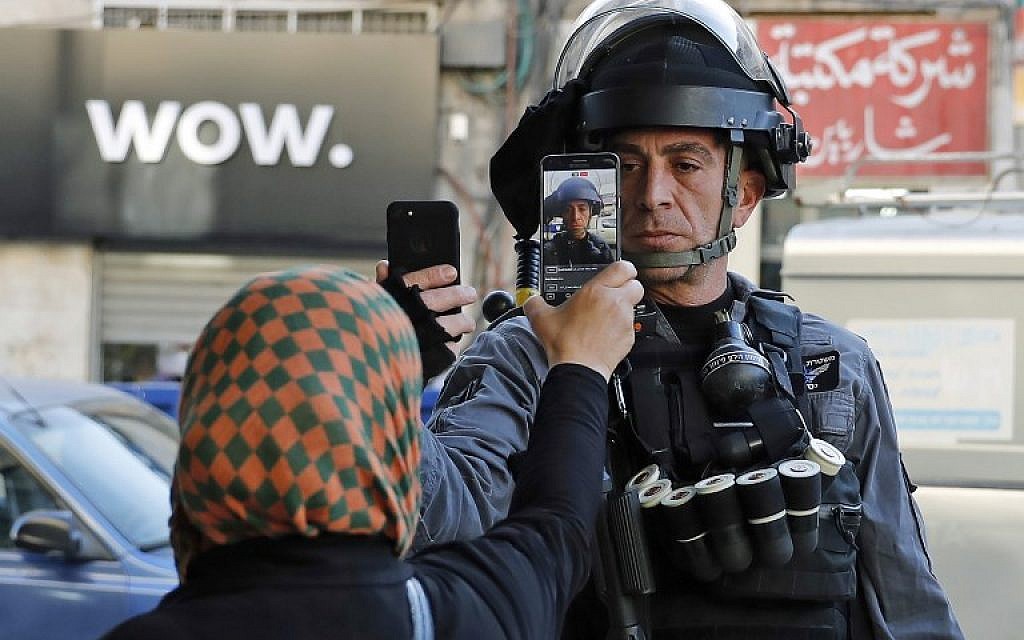 A Palestinian woman takes a picture of a member of the Israeli security forces as he takes her picture in a street in Jerusalem on December 16, 2017(AFP PHOTO / AHMAD GHARABLI)