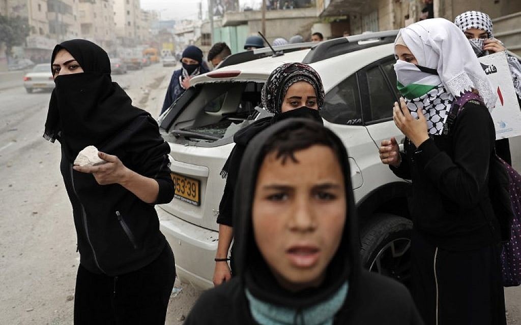 Female Palestinian protesters collect stones to throw towards Israeli security forces during clashes near the Qalandia checkpoint in the West Bank on December 20, 2017 as protests continue following the US president's recognition of Jerusalem as Israel's capital.(AFP PHOTO / THOMAS COEX)