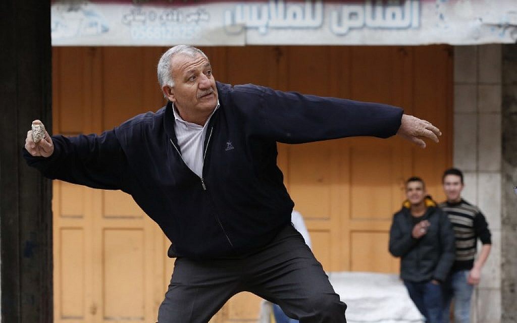 A Palestinian demonstrator throws stones towards Israeli security forces during clashes near a checkpoint in the city center of the West Bank town of Hebron on December 20, 2017. (AFP PHOTO / HAZEM BADER)