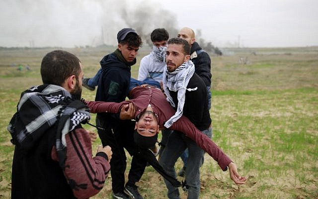 Palestinian protesters carry a wounded comrade during clashes with Israeli soldiers near the border fence east of Gaza City on December 22, 2017. (AFP PHOTO / MOHAMMED ABED) Palestinian protesters carry a wounded comrade during clashes with Israeli soldiers near the border fence east of Gaza City on December 22, 2017. (AFP PHOTO / MOHAMMED ABED)