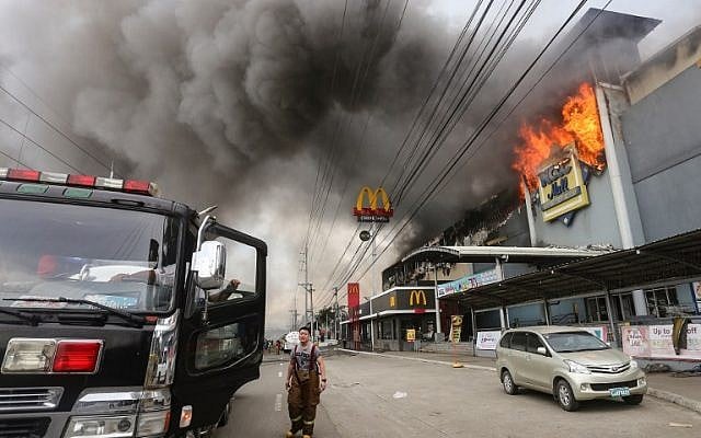 A firefighter stands in front of a burning shopping mall in Davao City on the southern Philippine island of Mindanao, December 23, 2017 (AFP PHOTO / MANMAN DEJETO) A firefighter stands in front of a burning shopping mall in Davao City on the southern Philippine island of Mindanao, December 23, 2017 (AFP PHOTO / MANMAN DEJETO)