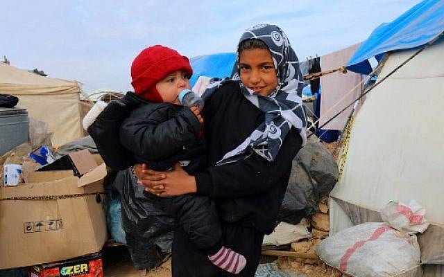 Syrian children, forced to leave their homes in the eastern cities of Deir Ezzor and Raqa by the war against the Islamic State (IS) group, pose outside a tent at the Ain Issa camp on December 18, 2017. (AFP PHOTO / Delil Souleiman) Syrian children, forced to leave their homes in the eastern cities of Deir Ezzor and Raqa by the war against the Islamic State (IS) group, pose outside a tent at the Ain Issa camp on December 18, 2017. (AFP PHOTO / Delil Souleiman)