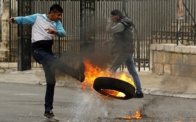 A Palestinian protestor kicks a burning tire during clashes with Israeli security forces in the West Bank city of Bethlehem on December 29, 2017, following the weekly Muslim Friday prayers. (AFP / Musa al Shaer)