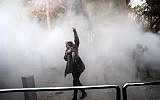 An Iranian woman raises her fist amid the smoke of tear gas at the University of Tehran during a protest driven by anger over economic problems, in the capital Tehran, December 30, 2017. (AFP/STR)