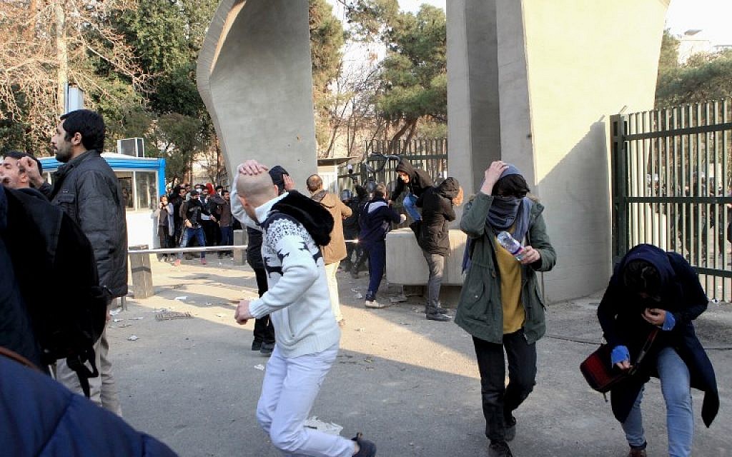 Iranian students run for cover from tear gas at the University of Tehran during a demonstration driven by anger over economic problems, in the capital Tehran on December 30, 2017. (STR/AFP)