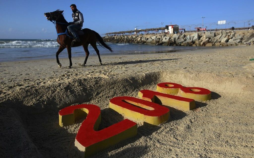 A Palestinian man walks past a 2018 sand writing at a beach in Gaza City on December 31, 2017 on the last day of the year. (AFP PHOTO / MOHAMMED ABED)