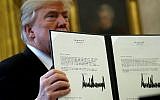 US President Donald Trump holds up a copy of legislation before signing the tax reform bill into law in the Oval Office December 22, 2017 in Washington, DC. (Chip Somodevilla/Getty Images/AFP)