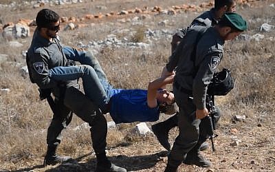 Illustrative: Border Police carry away a member of the "hilltop youth" during an evacuation of an illegal outpost in the northern West Bank. (Credit: Zman Emet, Kan 11)
