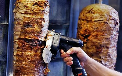 A man slices cuts of meat from a shawarma spit inside a restaurant cafe in Frankfurt, Germany, Thursday, November 30, 2017 (AP Photo/Michael Probst)
