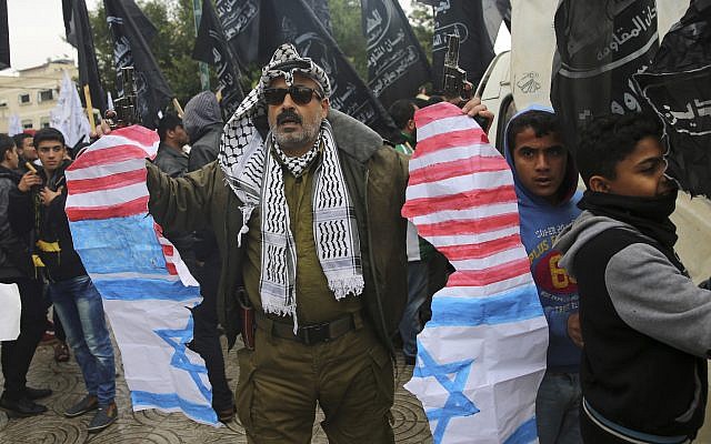 A protestor holds torn representations of American and Israeli flags during a protest at the Unknown Soldier Square in Gaza City, December 6, 2017. (Adel Hana/AP) A protestor holds torn representations of American and Israeli flags during a protest at the Unknown Soldier Square in Gaza City, December 6, 2017. (Adel Hana/AP)