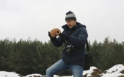 This photo from Dec. 5, 2017, shows an unidentified man holding human remains which had been removed from an old Jewish cemetery and dumped in huge mounds in Siemiatycze, Poland. (Aleksander Schwarz/The Union of Jewish Communities in Poland via AP)