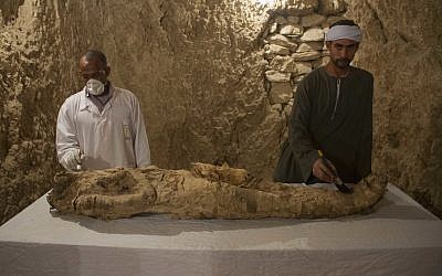 Egyptian excavation workers restore a mummy in a newly discovered tomb on Luxor's West Bank known as "KAMPP 150," December 9, 2017. (AP Photo/Hamada Elrasam)