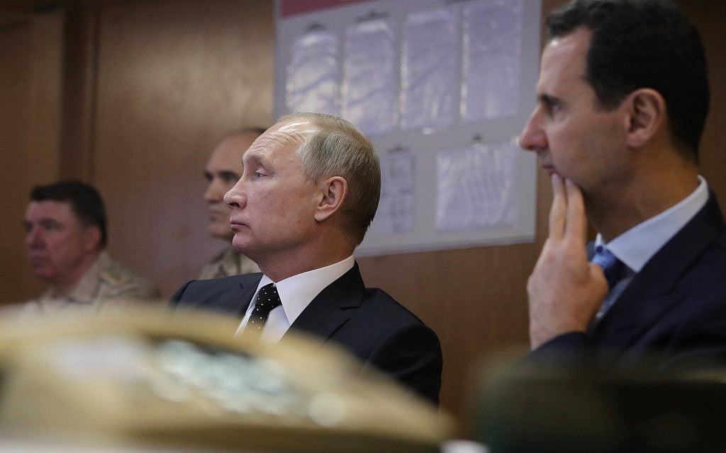 Russian President Vladimir Putin, center, and Syrian President Bashar Assad, 2nd right, meet with military personnel at the Hemeimeem air base in Syria, on Monday, December 11, 2017. (Mikhail Klimentyev, Sputnik, Kremlin Pool Photo via AP)