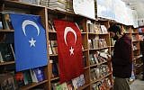 In this photo taken Thursday, Dec. 14, 2017, a man reads a book in a bookstore where flags which represents Turkey and 'East Turkistan,' the name Uighurs who oppose Chinese rule call their homeland, are hung in Istanbul's Zeytinburnu neighborhood. (AP Photo/Emrah Gurel)
